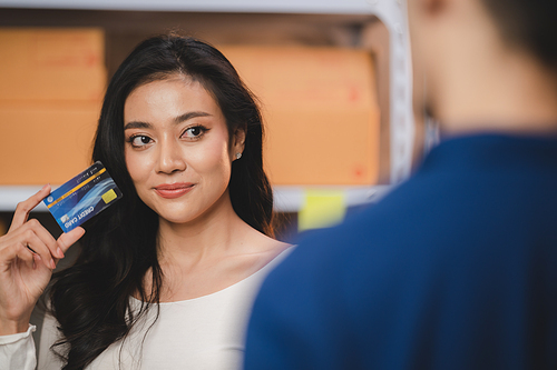 credit card and wireless POS terminal for card payment concept, Young Asian girl with a credit card received a parcel from a male delivery man The woman paid the male delivery man