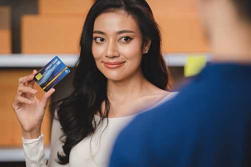 credit card and wireless POS terminal for card payment concept, Young Asian girl with a credit card received a parcel from a male delivery man The woman paid the male delivery man