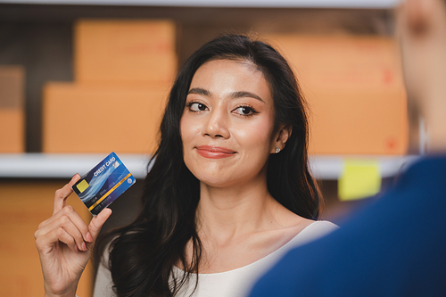 credit card and wireless POS terminal for card payment concept, Young Asian girl with a credit card received a parcel from a male delivery man The woman paid the male delivery man