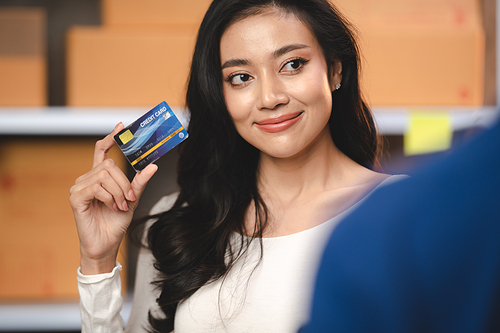 credit card and wireless POS terminal for card payment concept, Young Asian girl with a credit card received a parcel from a male delivery man The woman paid the male delivery man