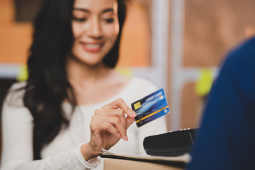 credit card and wireless POS terminal for card payment concept, Young Asian girl with a credit card received a parcel from a male delivery man The woman paid the male delivery man