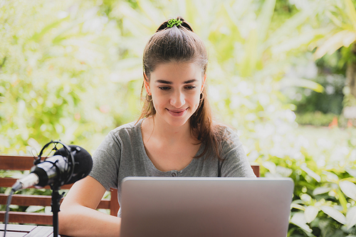 Funny and cheerful girl watching comedy movie on laptop with spectacles and pet dog while relaxing at home sitting on couch