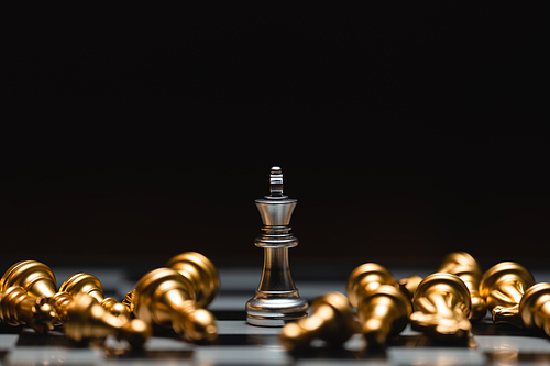 Close-up leader chess piece standing with falling silver pawn chess pieces on chessboard on dark background. Leadership and winner competition or business success teamwork strategy concept