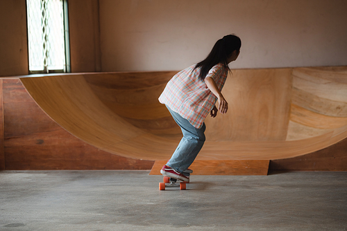 Asian women skater doing tricks jumping in the underground garage. Urban activity indoor lifestyle.