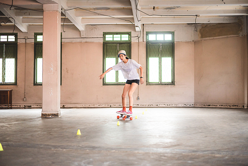 skateboard sport lifestyle, young Asian skater woman having fun with a board in a gym