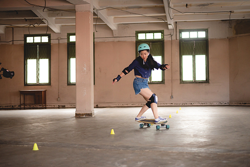 skateboard sport lifestyle, young Asian skater woman having fun with a board in a gym