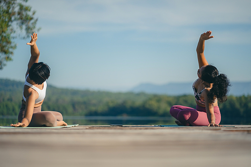 Group of people doing yoga exercises by the lake at morning outdoor, Woman practicing yoga in lotus position at park, Multinational women doing breathing exercises or yoga meditation during outdoor