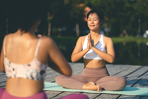Two beauty woman doing yoga on morning park, Yoga training strong woman best friends doing yoga at mountain, dressed in sportswear, woman practicing yoga in Pose Dedicated