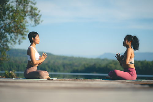 Two beauty woman doing yoga on morning park, Yoga training strong woman best friends doing yoga at mountain, dressed in sportswear, woman practicing yoga in Pose Dedicated