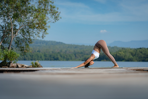 Beautiful attractive Asian woman practice fitness yoga pose on the pool above the Mountain peak in front of nature lake views, Feel so comfortable lifestyle and relax exercise in holiday morning