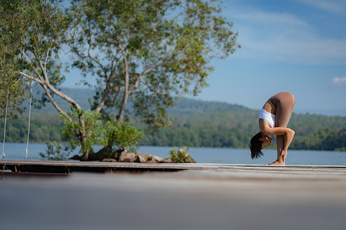 Beautiful attractive Asian woman practice fitness yoga pose on the pool above the Mountain peak in front of nature lake views, Feel so comfortable lifestyle and relax exercise in holiday morning