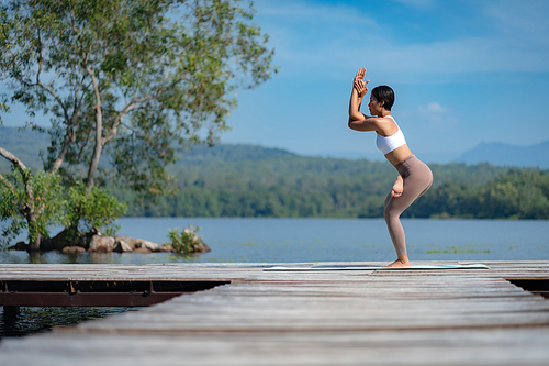 Beautiful attractive Asian woman practice fitness yoga pose on the pool above the Mountain peak in front of nature lake views, Feel so comfortable lifestyle and relax exercise in holiday morning