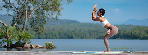 Beautiful attractive Asian woman practice fitness yoga pose on the pool above the Mountain peak in front of nature lake views, Feel so comfortable lifestyle and relax exercise in holiday morning