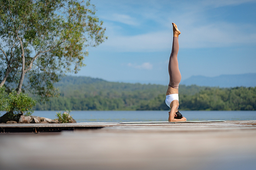 Beautiful attractive Asian woman practice fitness yoga pose on the pool above the Mountain peak in front of nature lake views, Feel so comfortable lifestyle and relax exercise in holiday morning