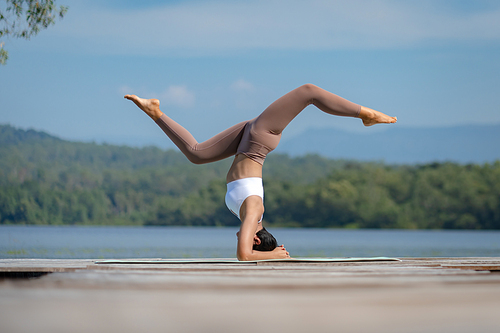 Beautiful attractive Asian woman practice fitness yoga pose on the pool above the Mountain peak in front of nature lake views, Feel so comfortable lifestyle and relax exercise in holiday morning