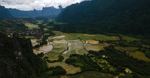 High angle view of tea garden and plantation farm surrounded by mountains and greenery against cloudy sky with no people around