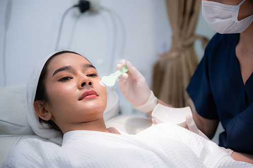 young Asian woman making treatment cosmetic beauty therapy on a face at cosmetological clinic