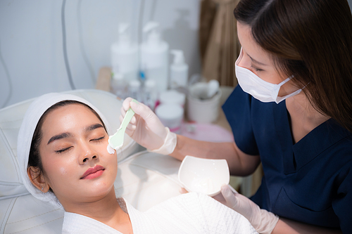 young Asian woman making treatment cosmetic beauty therapy on a face at cosmetological clinic