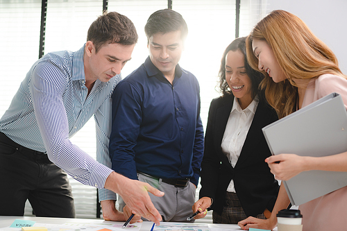 Employee business man give flip chart presentation to smiling colleagues at negotiations, workers laugh at office meeting, man present project or idea to happy coworkers at briefing