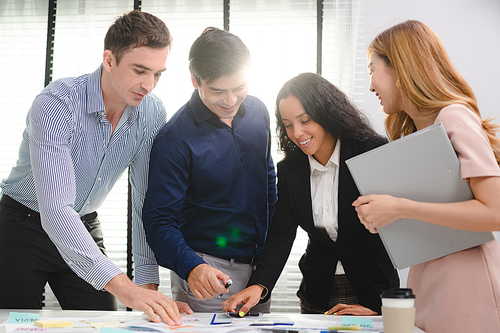 Employee business man give flip chart presentation to smiling colleagues at negotiations, workers laugh at office meeting, man present project or idea to happy coworkers at briefing