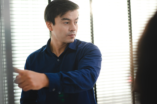 Employee business man give flip chart presentation to smiling colleagues at negotiations, workers laugh at office meeting, man present project or idea to happy coworkers at briefing