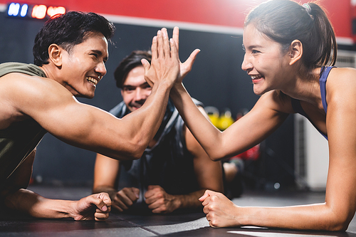 woman and man friends high fiving exercise while planking on a fitness gym floor, happy lifestyle to fit training together with teamwork for slim and healthy strength body by active sport