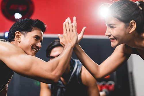 woman and man friends high fiving exercise while planking on a fitness gym floor, happy lifestyle to fit training together with teamwork for slim and healthy strength body by active sport