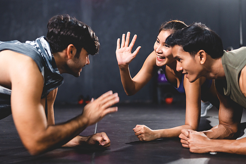 woman and man friends high fiving exercise while planking on a fitness gym floor, happy lifestyle to fit training together with teamwork for slim and healthy strength body by active sport