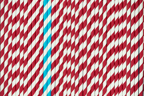 Creative arrangement of colorful drinking straws with deep red and blue stripes, directly above view