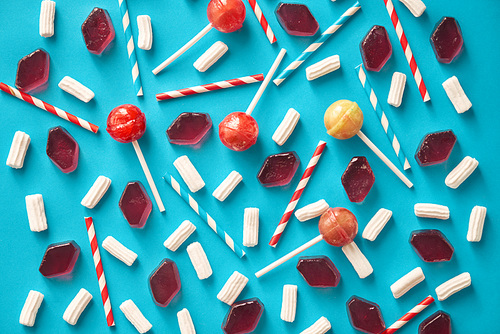 Directly above view of appetizing sweets and striped drinking straws creating colorful composition against turquoise background