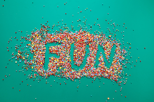 Fun word written on colorful sweet sprinkles, green background