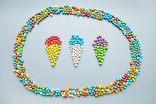 Colorful jelly beans laid out in shape of three ice creams inside of oval frame