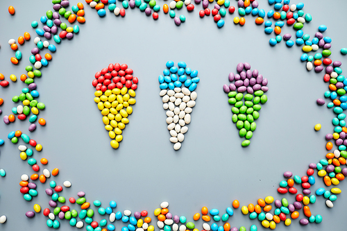 Jelly bean creativity: bright jellybeans laid out in shape of ice cream cones in frame on gray background