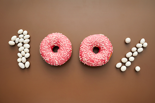 One hundred percent made of candy beans and doughnuts with topping, brown background