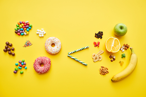 Choosing healthy sugar concept: sweets and baked food is less than fresh and dried fruits on bright yellow background