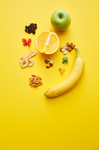 High angle view of cross section of orange, apple, banana, fried fruits and nuts on yellow background