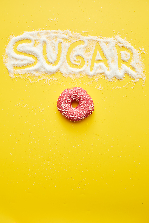 Much sugar in doughnut concept: sugar word written on powder and pink tasty doughnut on yellow background