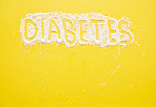 Diabetes word written on granulated sugar, bright yellow background