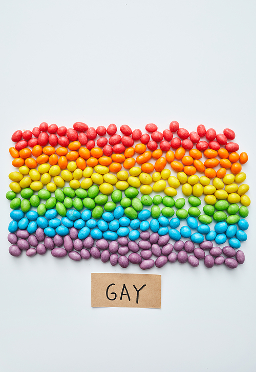 Colorful flag is symbol of freedom for gays: multi-colored sweet beans laid out in shape of equality flag and small tablet with gay word