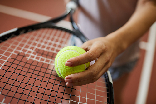 Close-up of unrecognizable woman putting tennis ball on racket while carrying out effort of serving before match