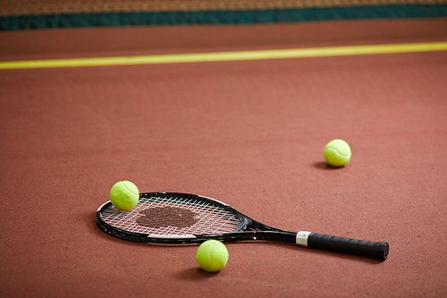 Close-up of modern tennis equipment scattered on floor of indoor tennis court, background of sports objects