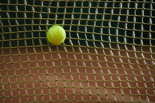 Close-up of tennis ball flying in net on sports court, defeat concept