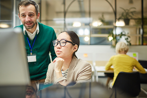 Confident advertising manager with stubble discussing idea with designer while they working on project