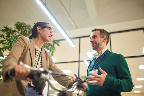 Mature conference speaker talking to young female participant sitting on modern electric bike