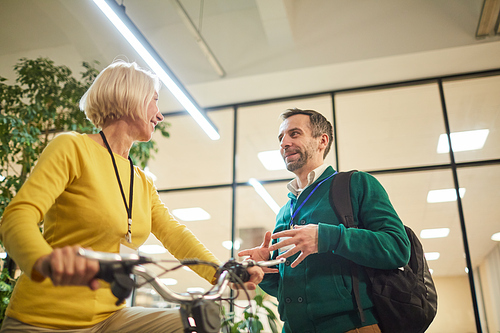 Smiling woman testing new model of electric bike and talking to its inventor at international exposition