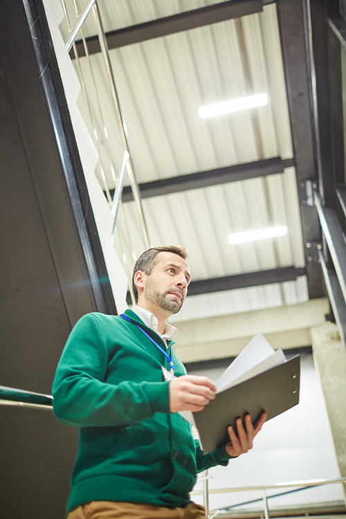 Frowning unhappy project manager standing in office with clipboard and documents