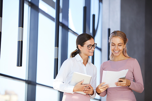 Cheerful excited young business experts standing in contemporary office and discussing market analysis together