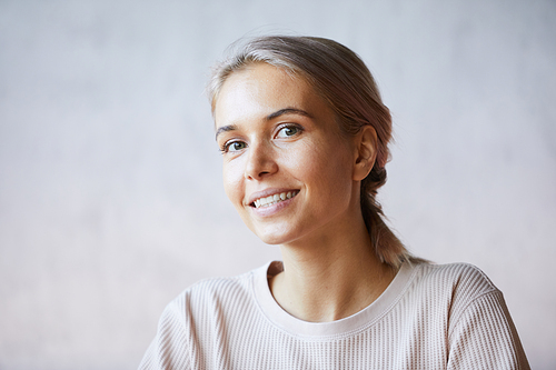 Portrait of cheerful pretty girl with ash-coloured hair wearing casual sweater, isolated background