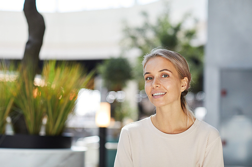 Portrait of smiling young ash-haired lady with pretty smile spending time in contemporary mall