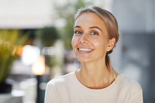 Portrait of happy confident young businesswoman with charming smile wearing casual sweater standing in lobby